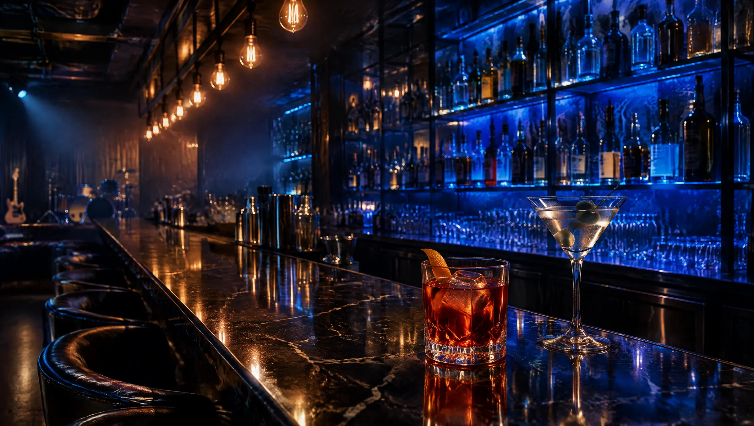 A long black marble bar with backlit shelves and two cocktails